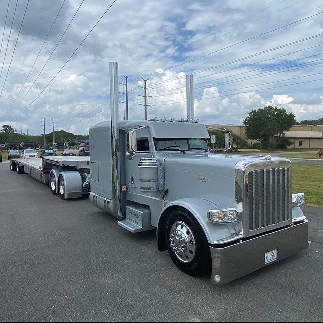 a large semi truck parked in a parking lot next to other cars and trucks on the road