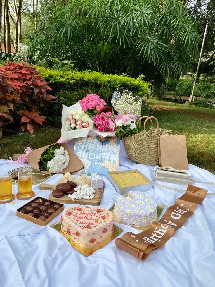 a table topped with cakes and desserts on top of a white cloth covered ground