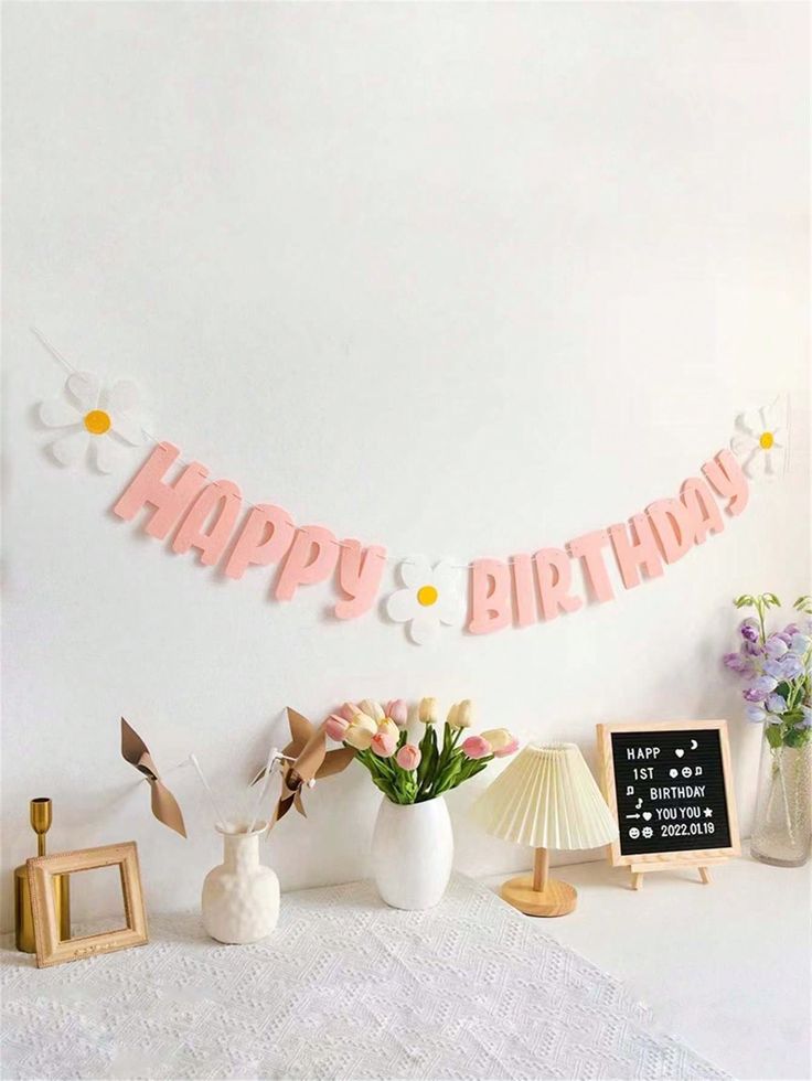 a white table topped with vases and flowers next to a sign that says happy birthday