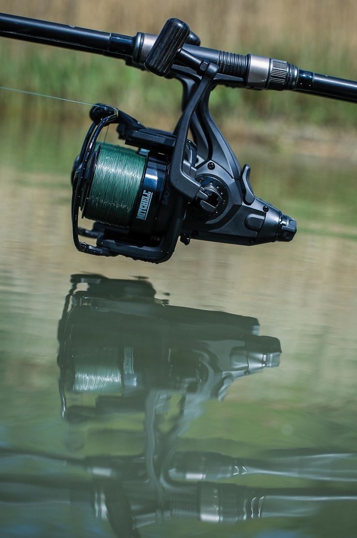 a fishing rod with a reel attached to it sitting in the water next to a body of water