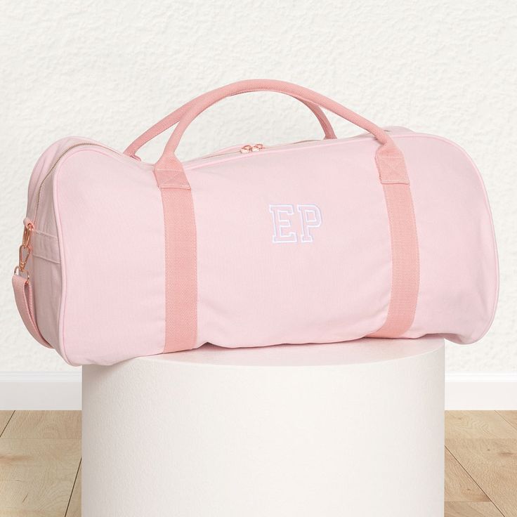 Paint a pretty picture in your imagination of how pleased your loved one will be when they receive this personalised, practical and pleasingly presentable pink canvas duffle bag. Roomy enough for everything you could need for a sleepover, day at the dance studio or fun weekend away, the pink duffle is complemented by a gorgeous rose gold zip to keep everything safe and sound. The ultimate travel accessory features sturdy cotton webbing carry handles making it easy to pick up and pop in the back of the car or even overhead compartment on a plane, plus a detachable and adjustable shoulder strap for those times you need to carry it that little bit further Make this a gift they’ll truly love for many travels trips to come with their own name or initials stylishly embroidered into the side, for Pink Rectangular Duffle Bag For School, Pink Rectangular Travel Bag As Gift, Pink Cotton School Bag, Everyday Pink Rectangular Duffle Bag, Pink Cotton Canvas School Bag, Cheap Trendy Pink Duffle Bag, Pink Cotton Canvas Travel Bag, Pink Rectangular Travel Bag For Gift, Trendy Pink Duffle Bag For On-the-go