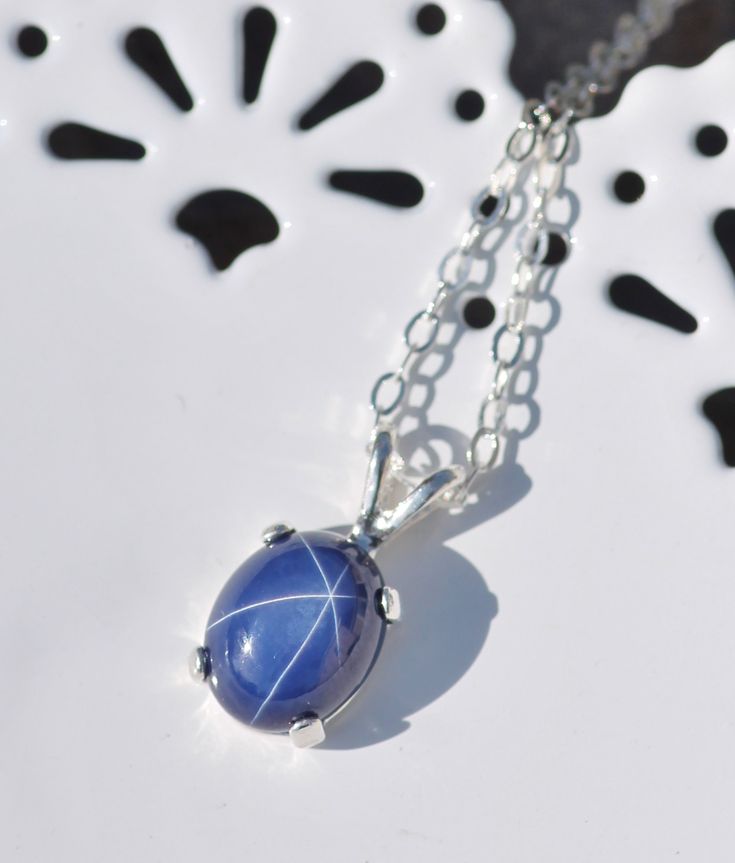 "A stunning new necklace made using a star sapphire gemstone. The sapphire is oval shaped and cabochon cut. It is excellent quality and set into a sterling silver prong setting. Lab grown Sapphire measures 10mm tall (just under 1/2\") while entire pendant is roughly 1/2\" tall. It hangs from sterling silver chain. Please choose desired chain length at checkout. Please see matching ring and earrings here: https://www.etsy.com/shop/hangingbyathread1?ref=search_shop_redirect&search_query=star+s Sapphire Jewelry With Oval Cabochon For Gift, Oval Sapphire Cabochon Necklace, Oval Sapphire Necklace With Cabochon Cut, Oval Sapphire Celestial Jewelry, Star Sapphire Gemstone, Sapphire Pendant Necklace, Oval Pendant Necklace, Sapphire Birthstone, Sapphire Necklace Pendants