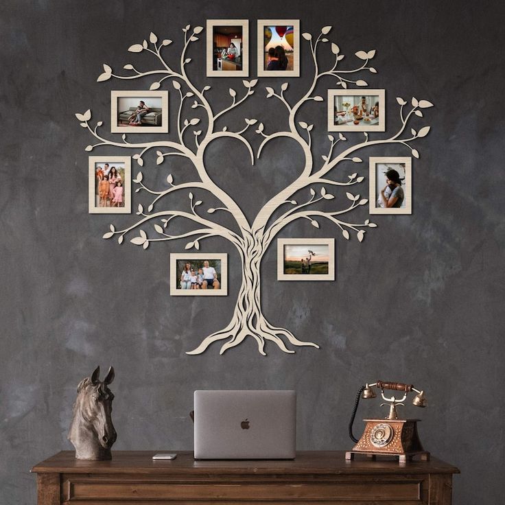 a laptop computer sitting on top of a wooden desk next to a tree with pictures