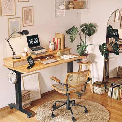 a desk with a laptop on top of it next to a chair and bookshelf