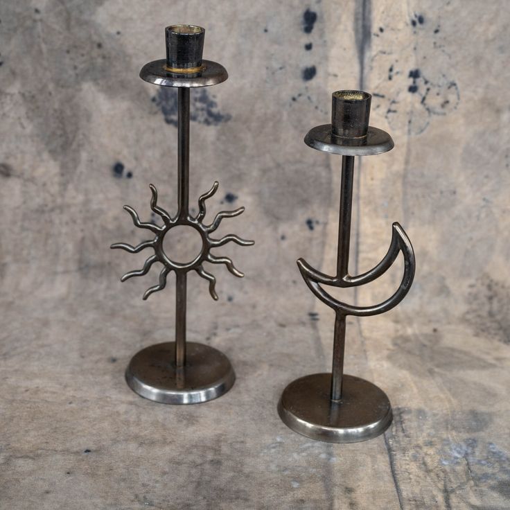 two metal candlesticks sitting next to each other on top of a stone floor