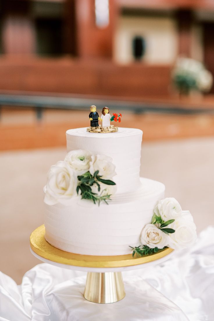 a wedding cake with white flowers and two figurines sitting on top of it