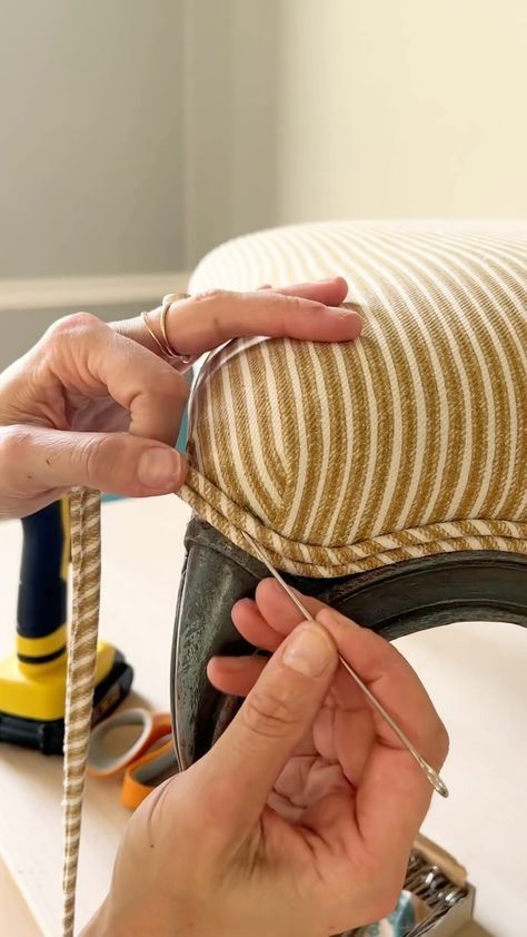 two hands are using scissors to trim the cushion on a chair that is being used as a sewing machine