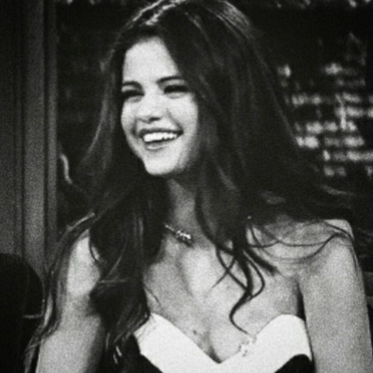 a black and white photo of a woman in a strapless dress smiling at the camera