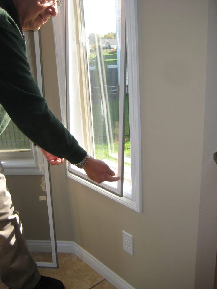 a man standing in front of a window with his hand on the window sill