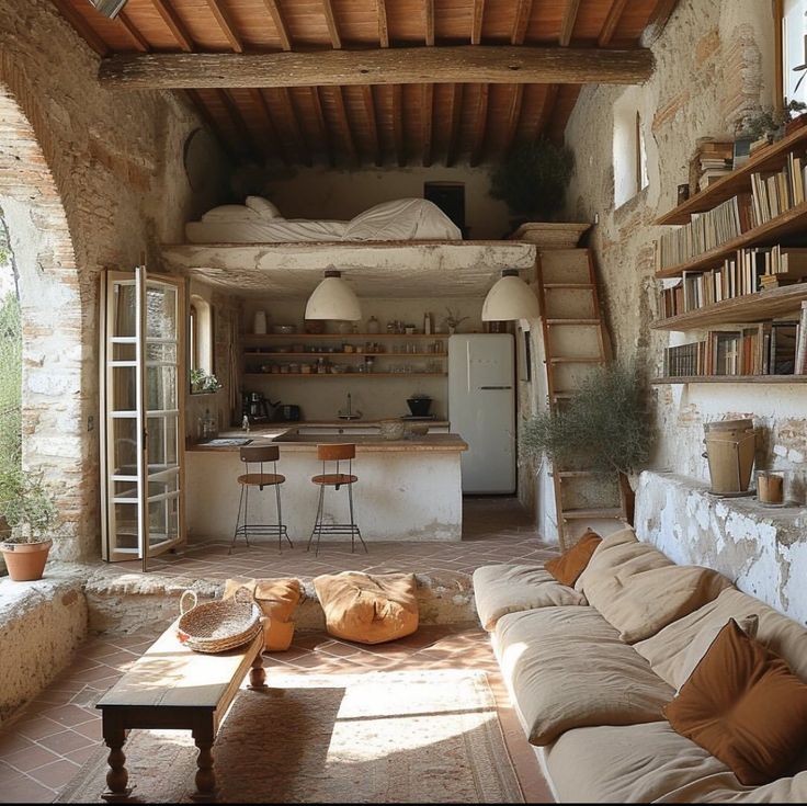 a living room filled with furniture next to a kitchen and dining area in an old stone building