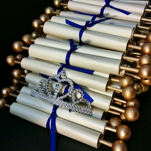 several rolls of white paper with gold and blue ribbon tied around them on black surface