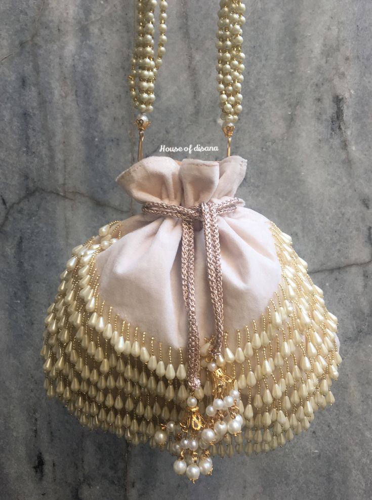 This is a beautiful handcrafted potli bag made with love.It has intricate handwork which showcases the Indian craftsmanship by our local artisans. It comes with a matching pearl handle. Details  - Both side handwork  - Fabric lining on the inside to keep your belongings safe  - Drawstring lock closure  - Detachable handle This clutch can be worn as a crossbody bag or a shoulder bag with the sling chain or can simply be carried in hand.It is spacious enough to carry mobile phones, lipsticks, Keys Bohemian Potli Bag For Receptions And Festivals, Bollywood Style Potli Bag For Reception, Reception Potli Bag With Pearl Embroidery, Elegant Potli Bag With Gota Work For Reception, Handmade Potli Bag For Reception, Elegant Gota Work Potli Bag For Party, Traditional Gota Work Bag For Reception, Festive Pearl Embroidery Evening Bag, Festive Pearl Embroidered Evening Bag As Gift