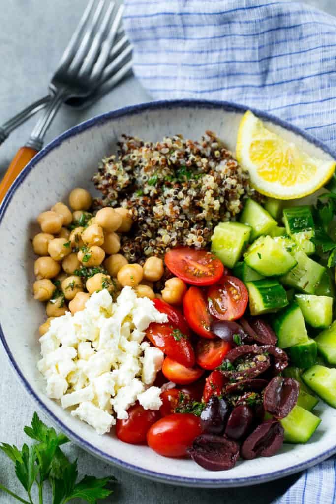 a bowl filled with vegetables and chickpeas on top of a blue towel next to a fork