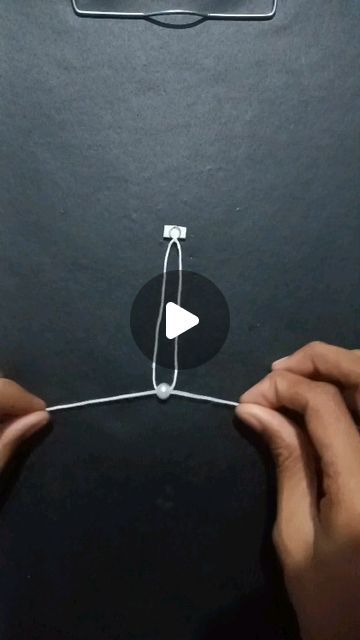 two hands holding wires connected to the back of a black box with an arrow on it