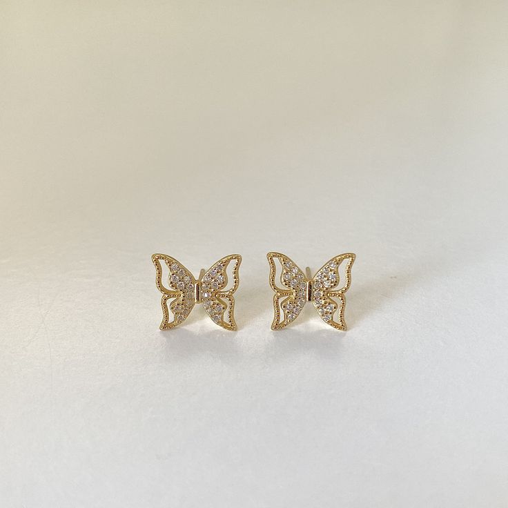 Introducing the Glimmering Golden Butterfly S925 18k Gold-Plated Stud Earrings, a pair of exquisite, finely crafted additions to our Deja vu Jewellery collection. These earrings are fashioned from pure S925 silver and plated with 18k gold, offering a lustrous, warm tone that flatters every skin type. Each stud is designed to resemble a butterfly mid-flight, its wings beautifully spread and adorned with dazzling white zirconia stones. These stones catch the light brilliantly, adding an extra touc Butterfly White Gold Earrings For Gift, Butterfly Shaped White Gold Earrings For Gift, Gold Butterfly Earrings Fine Jewelry, Gold Butterfly Fine Jewelry Earrings, 14k Gold Butterfly Earrings For Anniversary, Elegant Gold Butterfly-shaped Earrings, Elegant Gold Butterfly Earrings, Butterfly-shaped Yellow Gold Earrings For Anniversary, Elegant Butterfly Earrings For Everyday