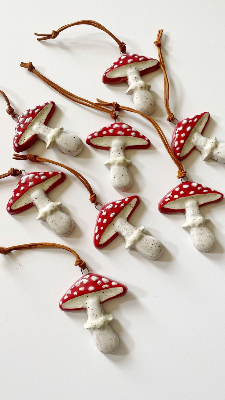 small red and white mushroom ornaments hanging from a tree branch on a white table top