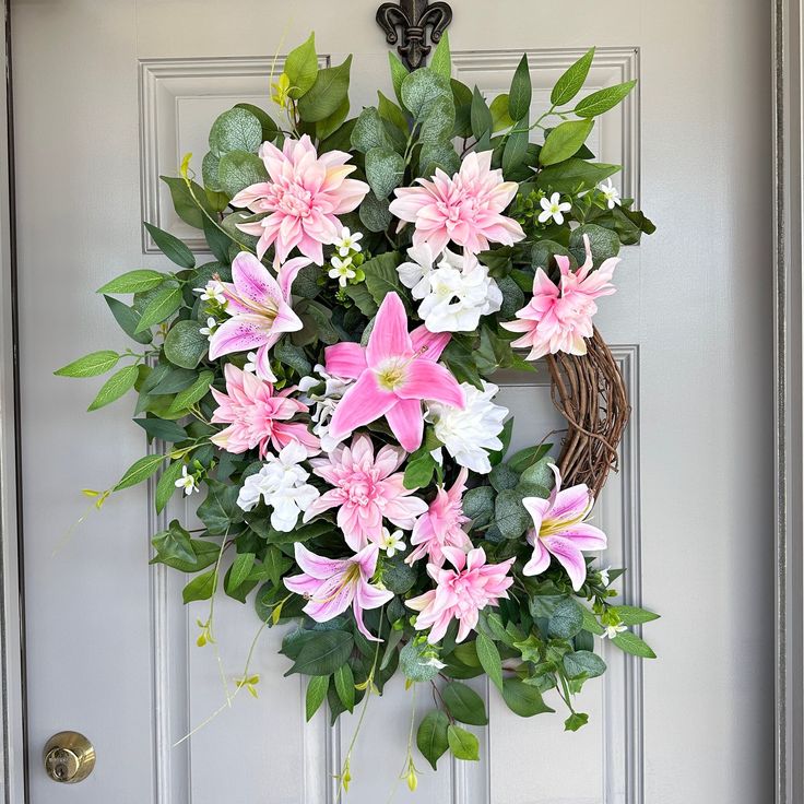 a wreath with pink and white flowers hanging on a door