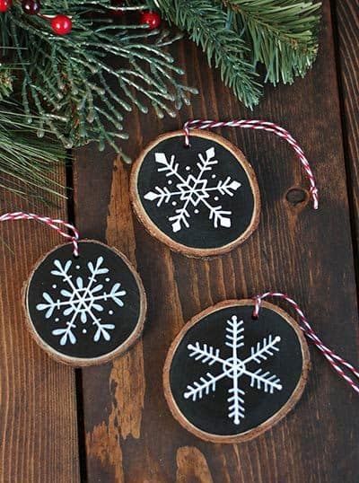 three wood slices with snowflakes on them hanging from a christmas tree ornament