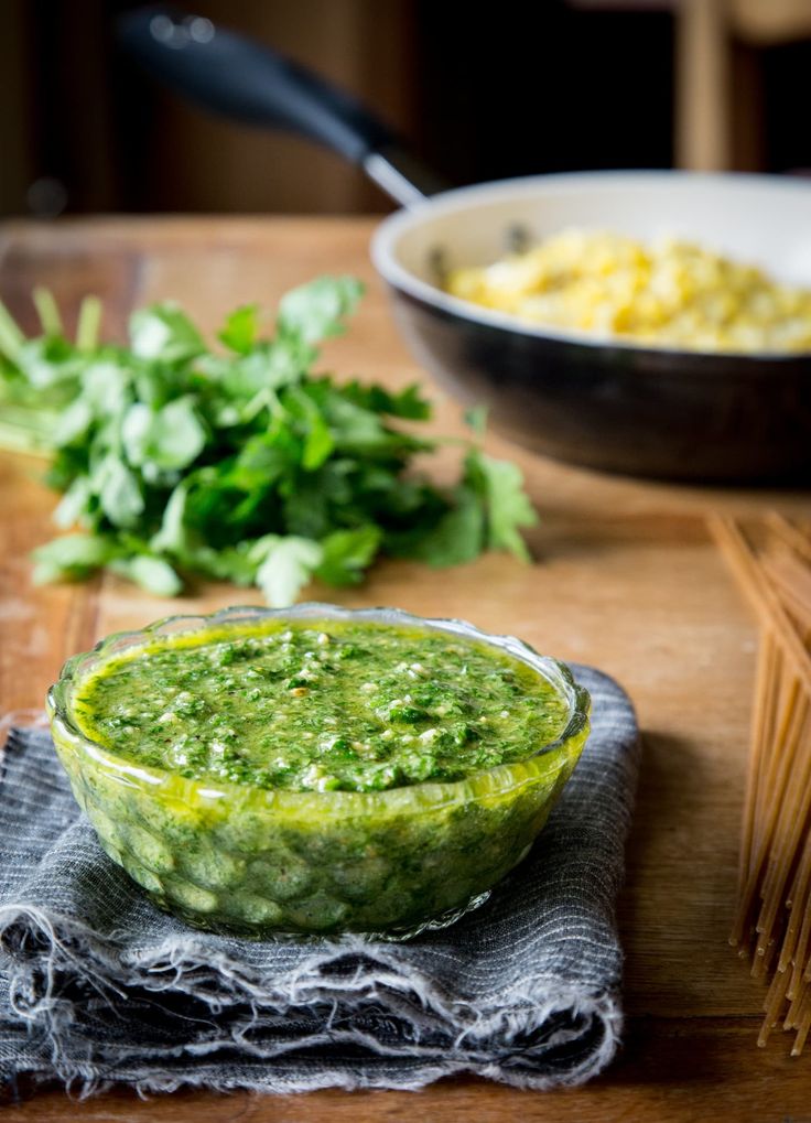 a bowl filled with green sauce next to some vegetables