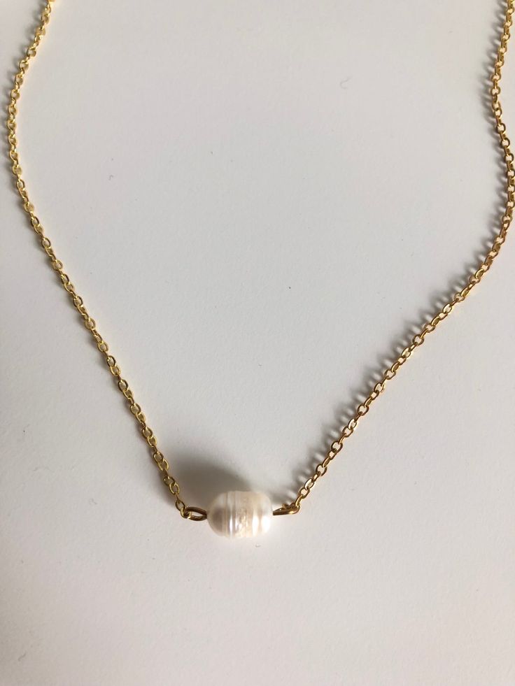 In the Philippines pearls are a national gem! They represent the richness of beauty the stunning sea life brings to the islands. A simple single pearl sits in the center of this gold filled chain. 15" long. Gold Single Strand Baroque Pearl Jewelry, Gold Pearl Pendant Necklace In 14k Gold Filled, Minimalist Pearl Pendant Jewelry With Round Beads, Elegant Gold Shell Necklace With Pearl Charm, Elegant Gold Shell Necklace With Pearl Drop, 14k Gold Filled Pearl Chain Necklace, White 14k Gold Pearl Drop Necklace, Gold Adjustable Pearl Drop Necklace, Gold Charm Necklace With Pearl Charm And Round Beads