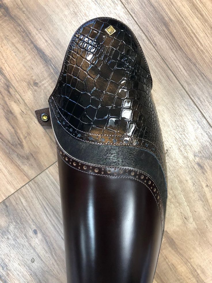 a close up of a black boot on a wooden floor