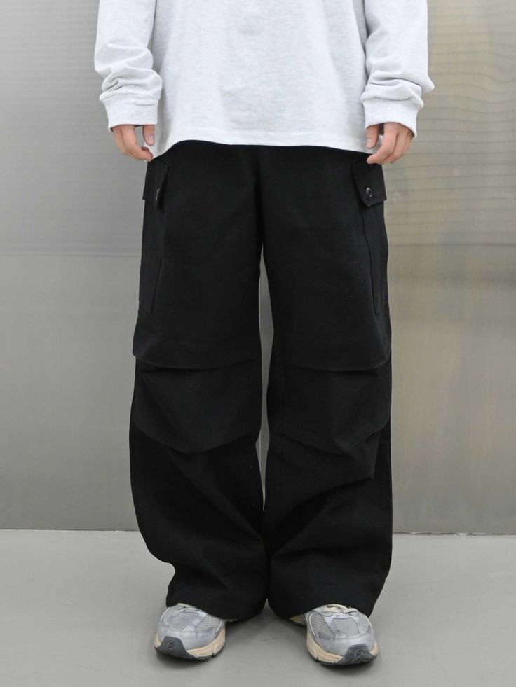 It is a comfy wide fit cargo pant for unisex. The durable and steep cotton twill fabric makes perfect fit. The pant has features of parachute pants such as horizontal pleats on the front. The cargo pockets have buttons to store items securely. The size and silhouette are adjustable using drawstrings on the waist and on the hem. - Elastic waist with drawstring - Side pockets- Back pockets - Symbol patch Cotton Techwear Parachute Pants With Pockets, Cotton Parachute Pants With Multiple Pockets For Outdoor, Cotton Parachute Pants With Multiple Pockets For Outdoor Activities, Urban Black Parachute Pants With Patch Pockets, Black Urban Parachute Pants With Patch Pockets, Cotton Cargo Pants In Techwear Style, Techwear Wide Leg Parachute Pants With Patch Pockets, Baggy Techwear Parachute Pants With Multiple Pockets, Baggy Black Work Pants With Cargo Pockets