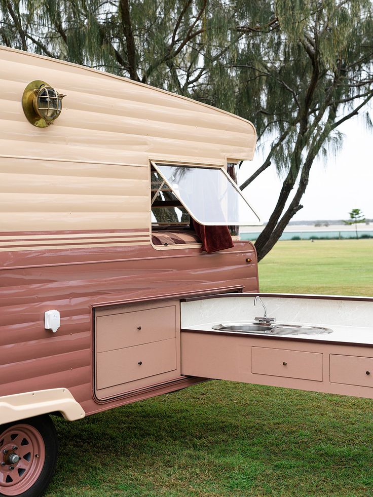 an old camper is parked in the grass with its door open and windows opened