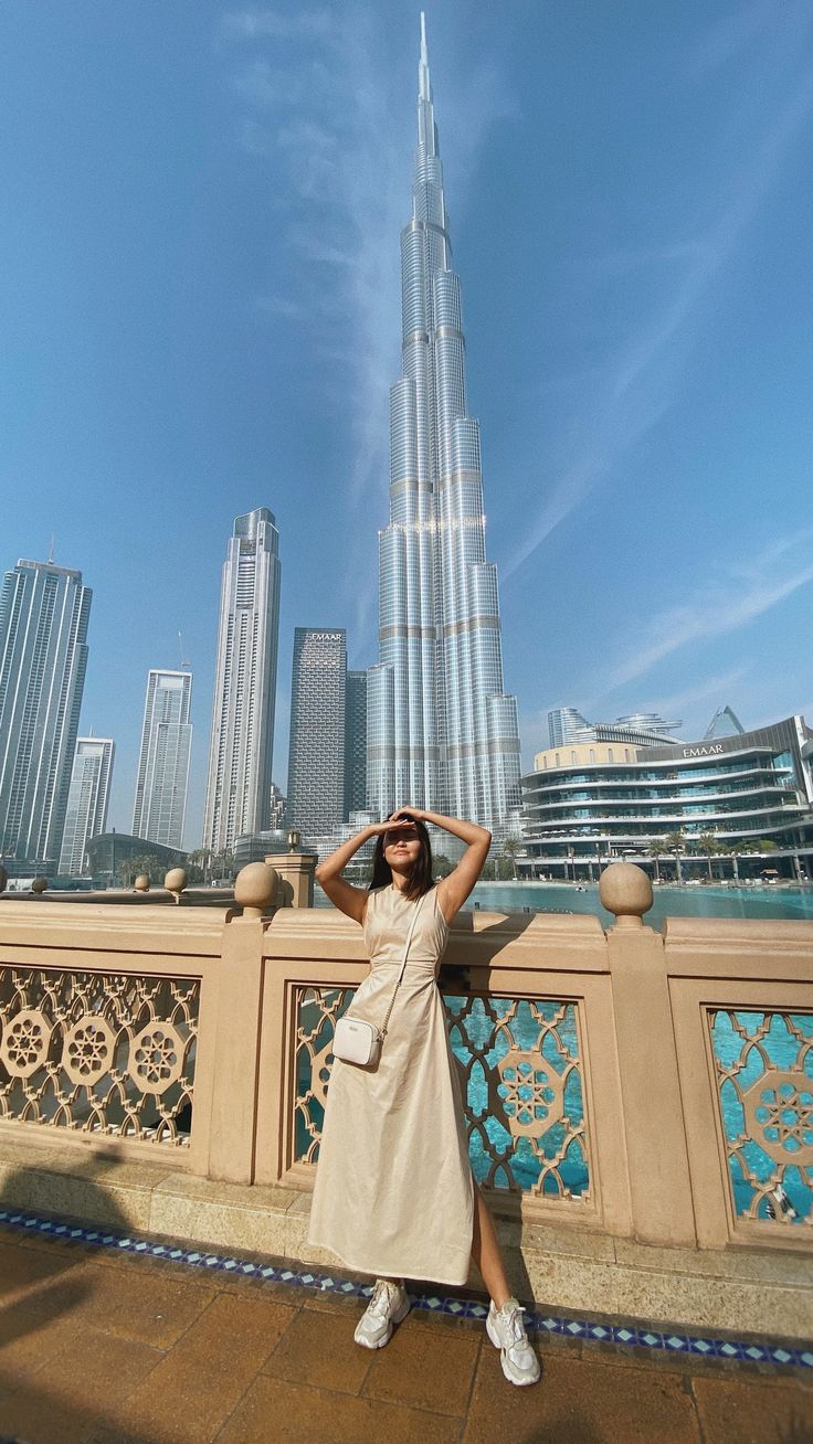 a woman standing on top of a bridge in front of a tall buliding