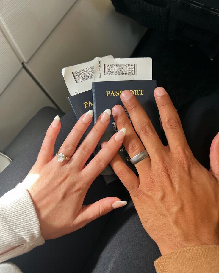 a woman holding onto a passport while sitting in an airplane with her hands on the book