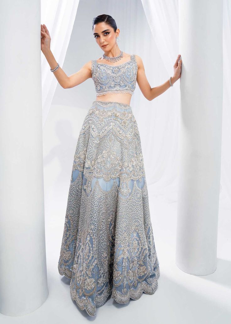 Indian Bridal Dress in Wedding Blue Choli Lehenga Style is a stunning attire adorned with hand-crafted details of embellishments. The alluring details of pearls, sequins, motifs, and embroidery make this beautiful Lehenga Choli dress an epitome of beauty and grace. Lehenga Choli: The choli in an alluring ice blue shade is intricately emblazoned with zardosi and hanging motifs. This choli in beautiful sleeveless style is adorned with shimmering silverwork, naqshi, tilla, beads, and sequins, makin Anarkali Style Hand Embellished Sharara For Ceremony, Anarkali Ceremony Sets Hand Embellished, Traditional Hand Embellished Sharara For Ceremony, Traditional Hand Embellished Blue Choli, Blue Anarkali Dress For Ceremony, Blue Hand Embellished Sharara For Reception, Blue Hand Embellished Choli For Reception, Hand Embellished Floor-length Sets For Ceremony, Blue Hand Embellished Floor-length Choli