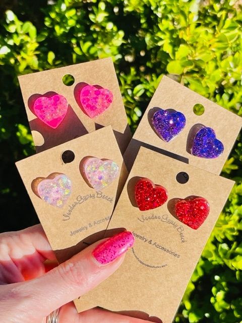 hand holding four different colored heart shaped magnets