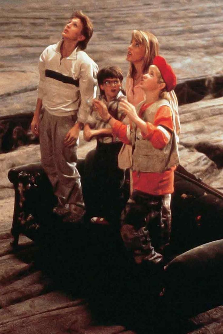 three people standing on top of a boat in the water with one person pointing at something