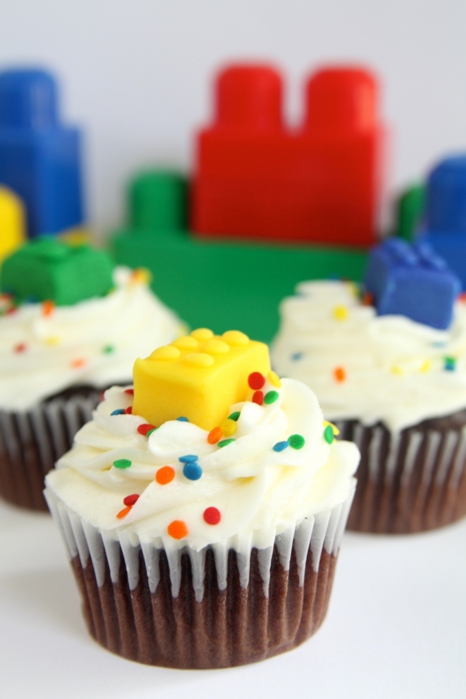 three cupcakes with white frosting and lego blocks in the background