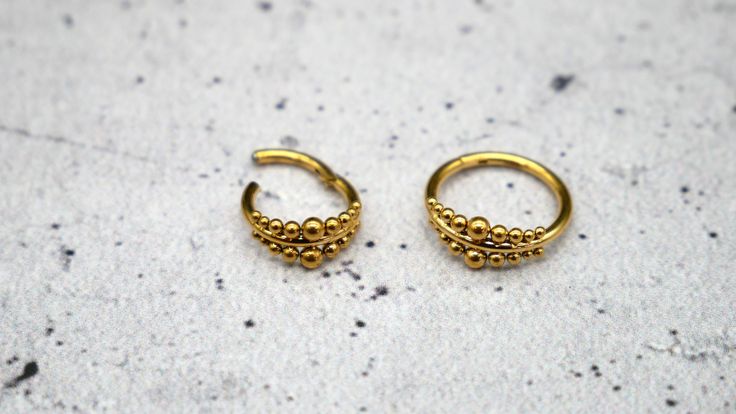 two small gold hoop earrings sitting on top of a white surface with tiny beads in the middle