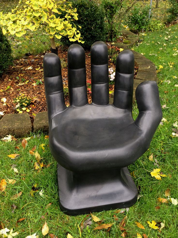 a black hand statue sitting on top of a lush green field