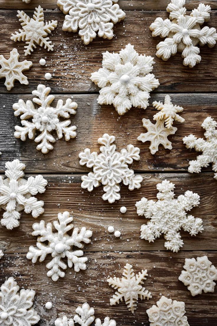 white snowflakes are arranged on a wooden surface, all in different sizes and shapes