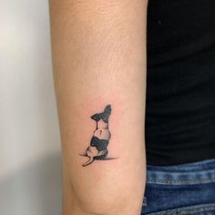 a small black and white dog tattoo on the left arm by a woman's hand