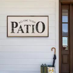 a welcome sign on the side of a house with an umbrella and boots in front