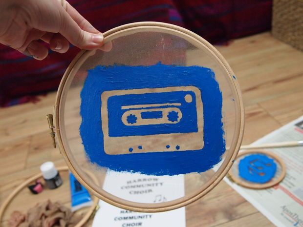 a person holding up a blue and white painting with a radio on it's side