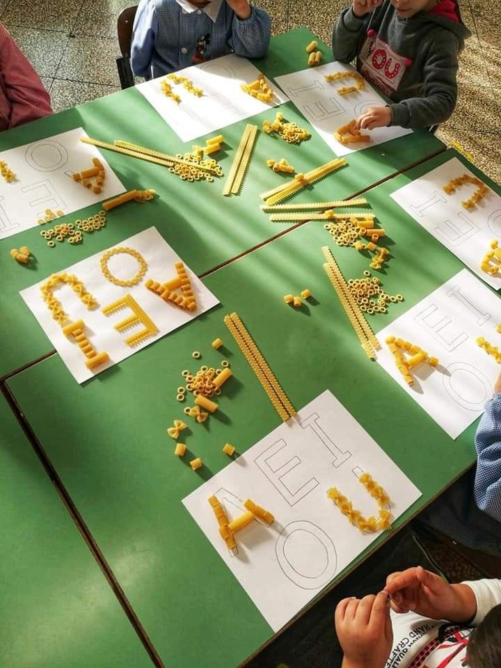 children sitting at a table working on letters and numbers