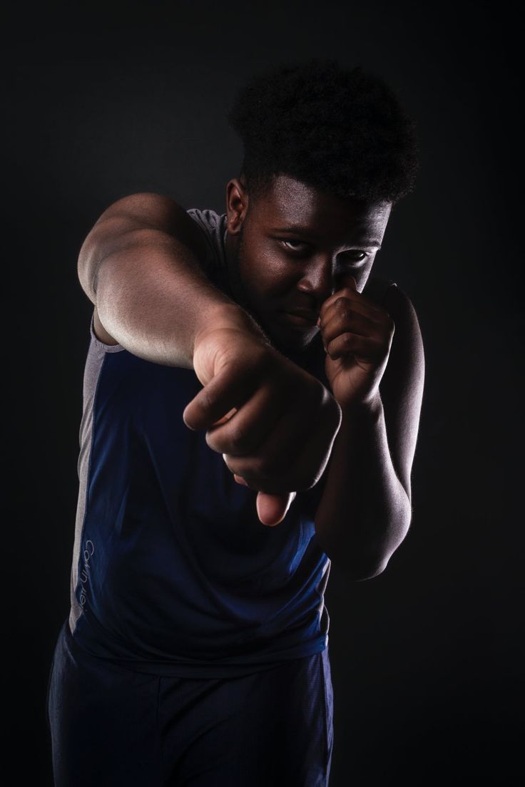 a man pointing at the camera with his hand on his hip while wearing a blue tank top