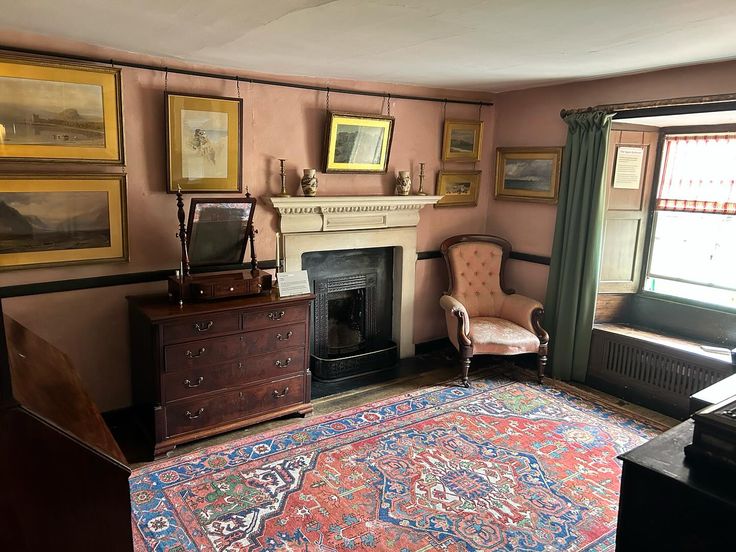 a living room filled with furniture and a rug on top of a wooden floor next to a fire place