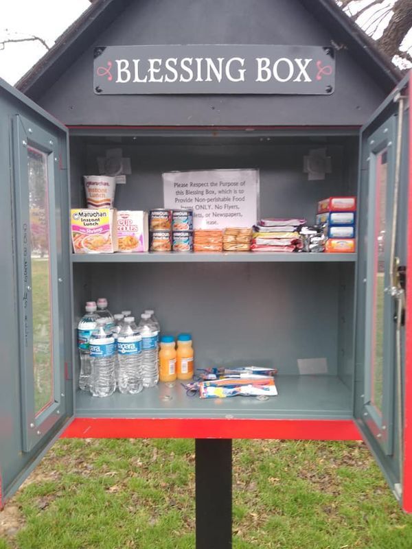 an outhouse with food and drinks on the shelves in it's display case