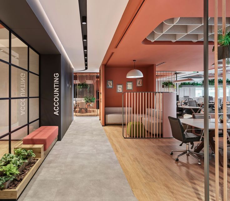 an office with wood flooring and orange walls, along with plants on the desks