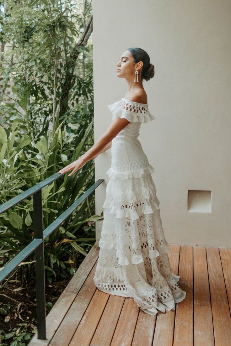 a woman in a white dress is standing on a wooden deck and looking up at the sky