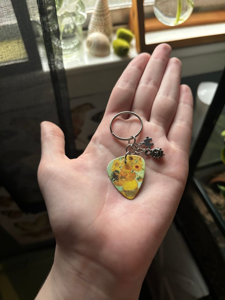 a hand holding a keychain with an image of a cat and flower on it