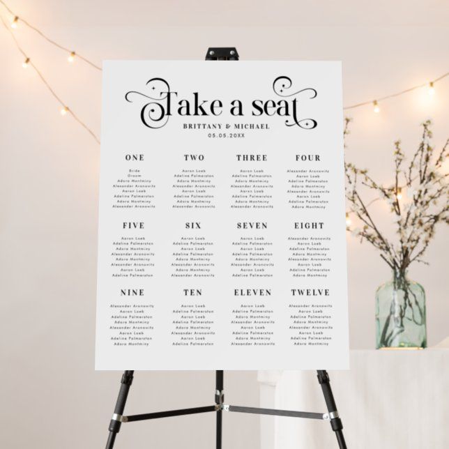 a table plan sitting on top of a easel next to a vase filled with flowers