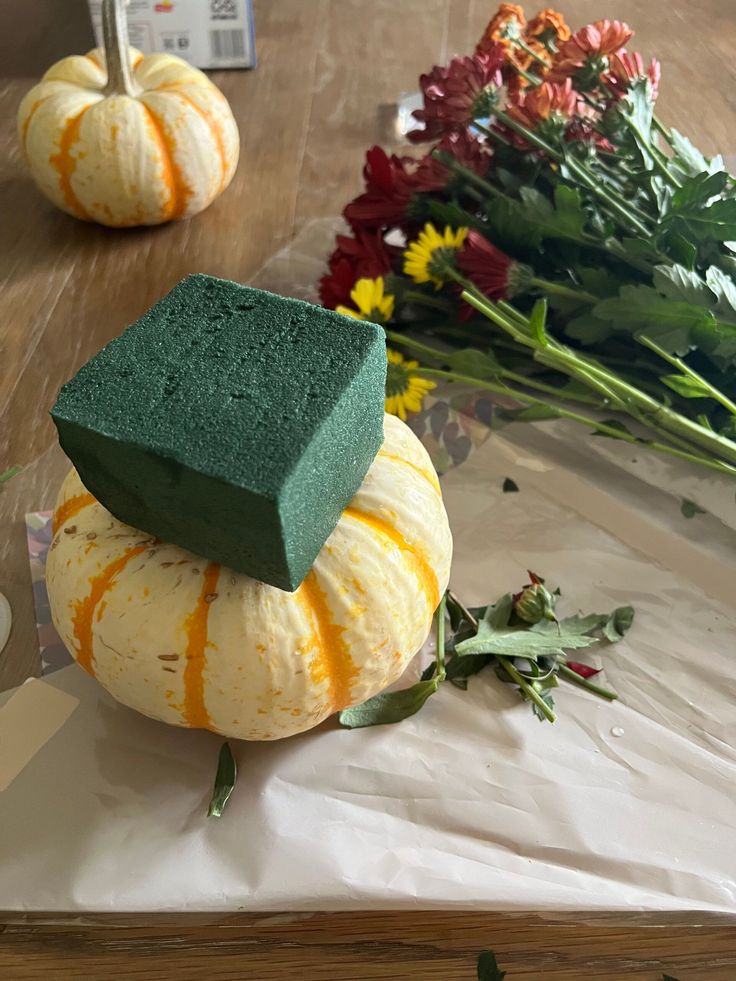 two pumpkins and some flowers on a table