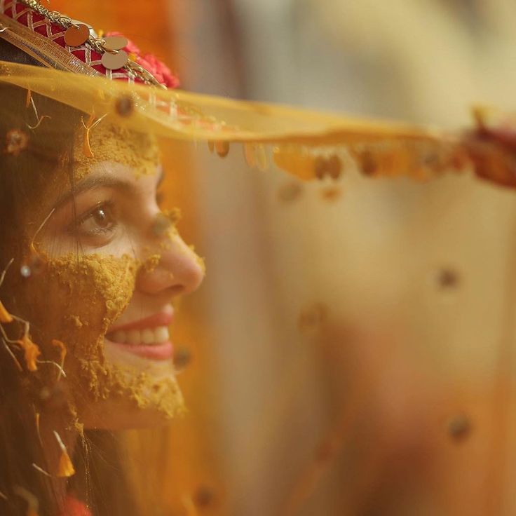 a woman with yellow powder on her face wearing a headdress and gold jewelry