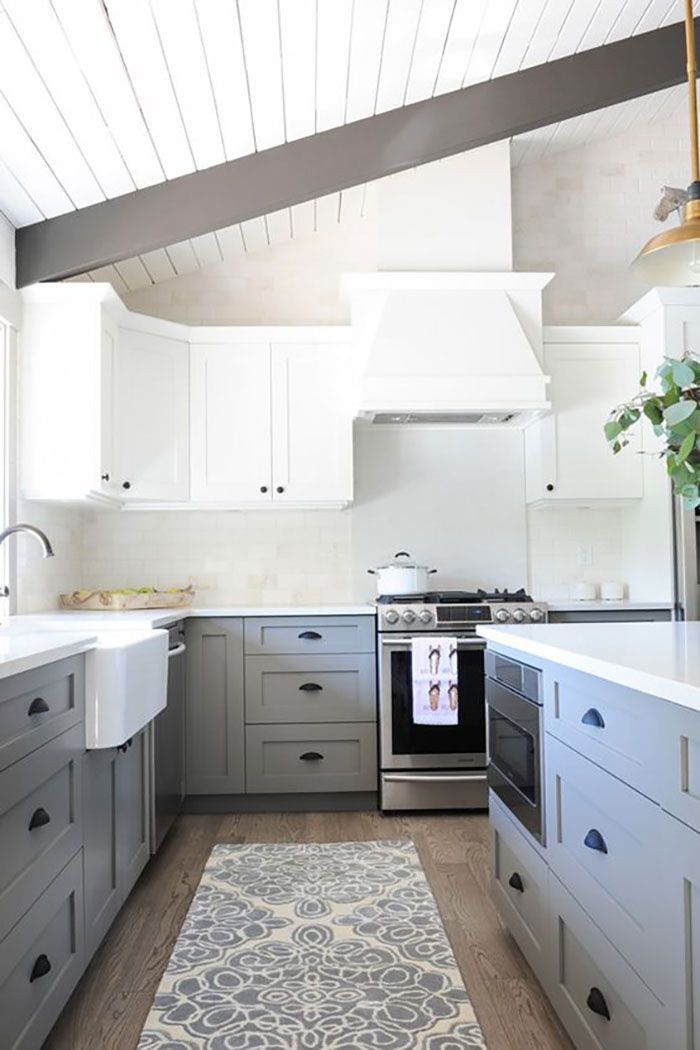 a kitchen with gray cabinets and white counter tops, an area rug on the floor